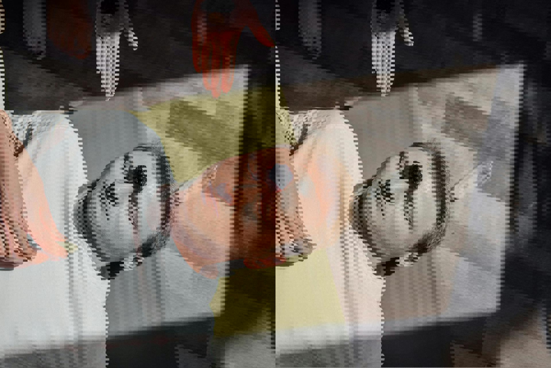 Eine Person liegt auf einer Matte mit einem schwarzen Gegenstand auf der Stirn.