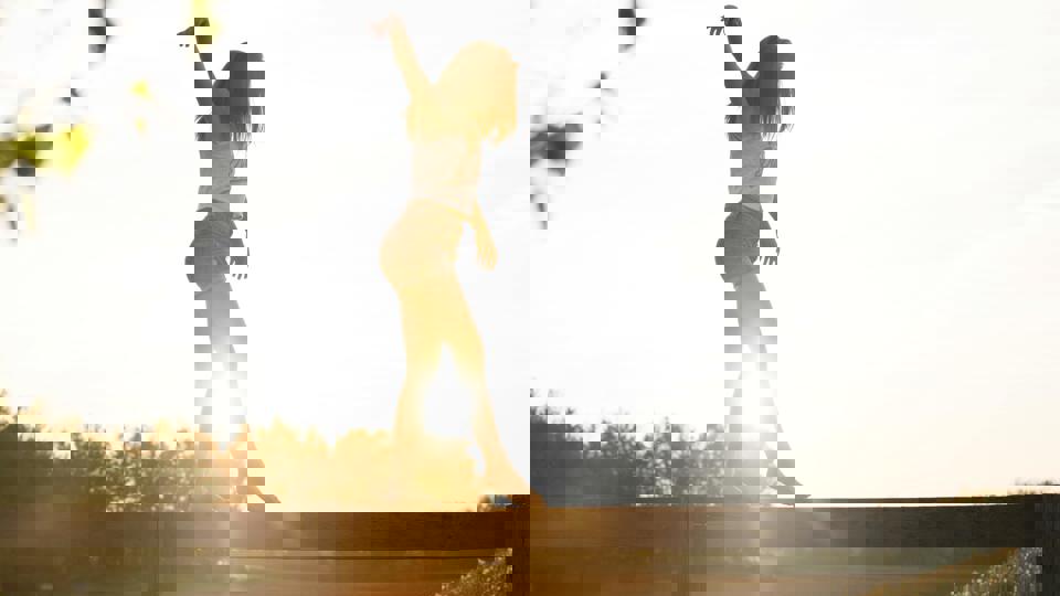 Eine Person steht auf einem Geländer mit erhobenen Armen.