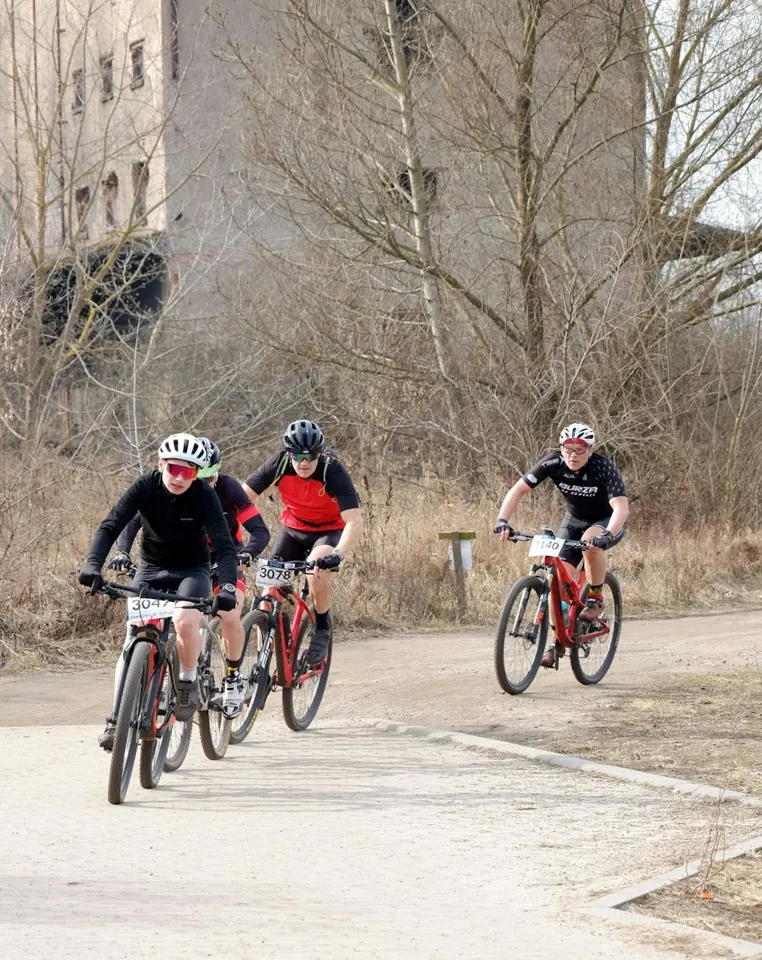 Eine Gruppe von Menschen fährt mit Fahrrädern auf einem unbefestigten Weg.
