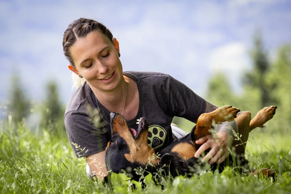 eine Person, die mit einem Hund im Gras liegt