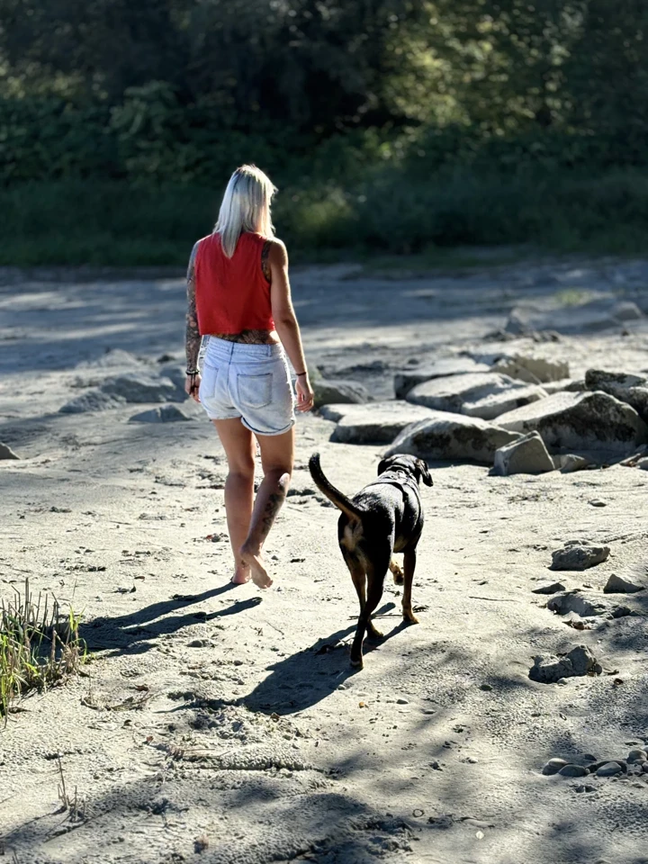 Hundetrainerin aus Texing, die mit einem Hund am Strand spazieren geht