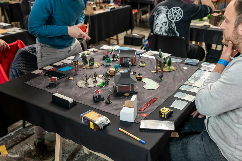 eine Gruppe von Menschen, die um einen Tisch mit einem Spielbrett sitzen