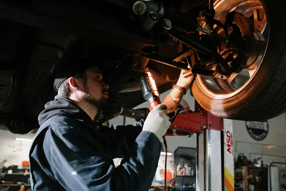 eine Person, die unter einem Auto arbeitet