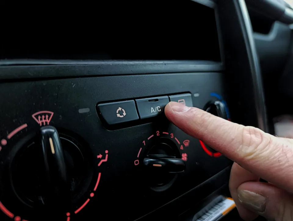 Ein Finger, der einen Knopf auf einem Armaturenbrett eines Autos drückt.