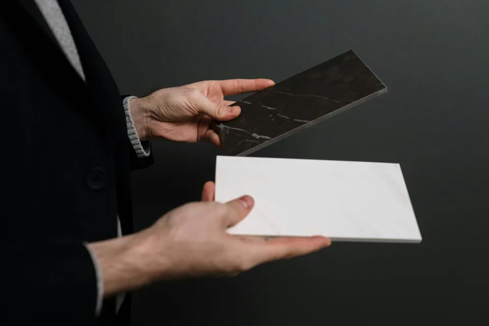 eine Person, die eine weiße und schwarze Fliese hält