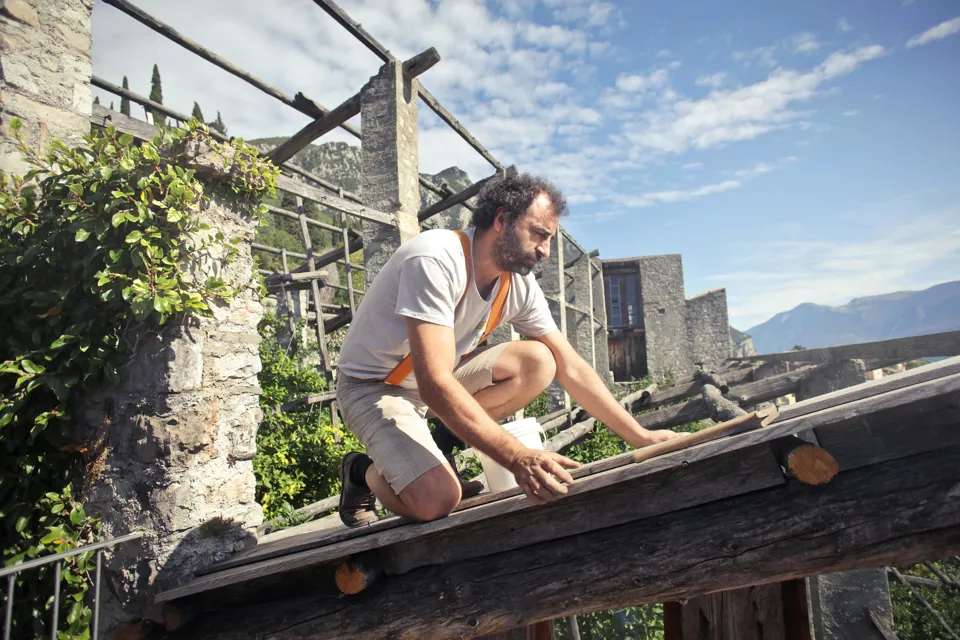eine Person, die auf einem Holzbalken kniet