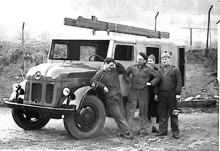 eine Gruppe von Männern, die neben einem Lastwagen stehen