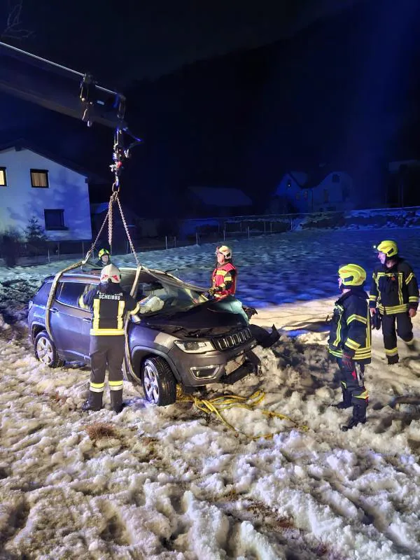 Eine Gruppe von Menschen steht im Schnee um ein Auto herum.