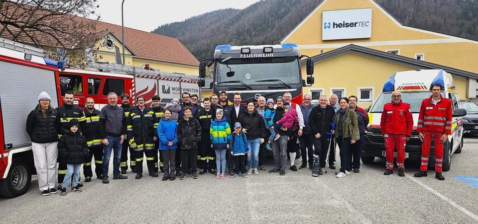 Eine Gruppe von Menschen steht vor einem Feuerwehrauto.