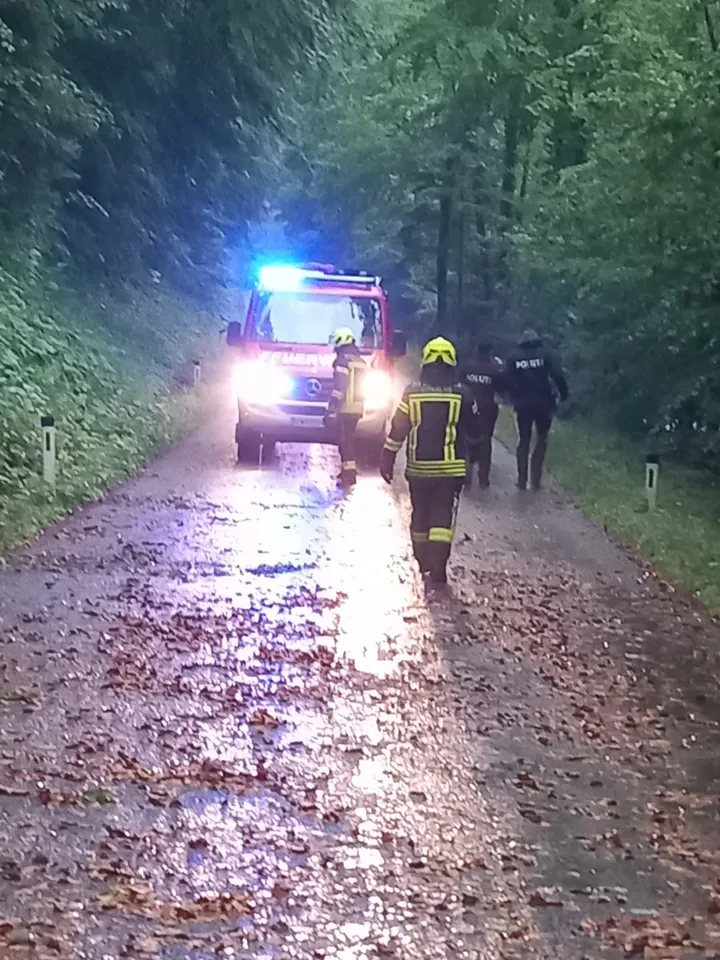 Eine Gruppe von Personen in Feuerwehruniformen, die auf einer Straße mit einem Lastwagen gehen.