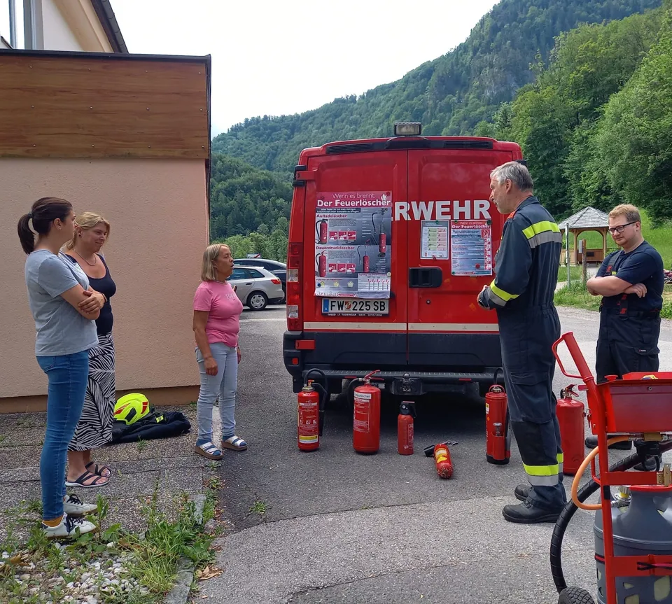 eine Gruppe von Menschen, die um ein Feuerwehrauto stehen