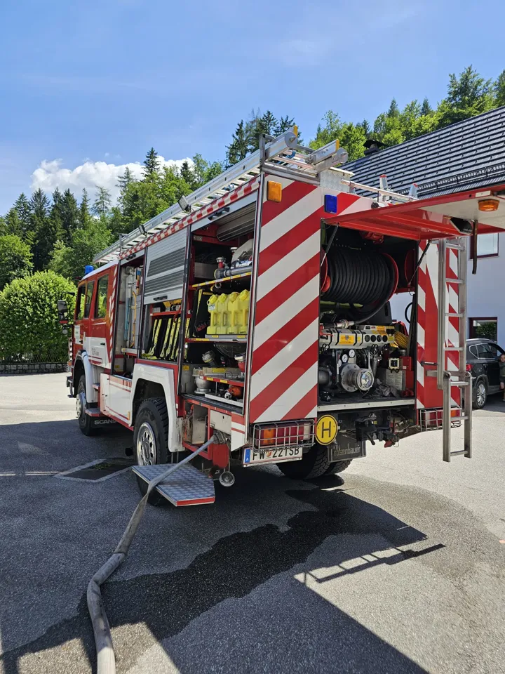 Ein Feuerwehrauto mit einem Schlauch, der an der Rückseite befestigt ist.
