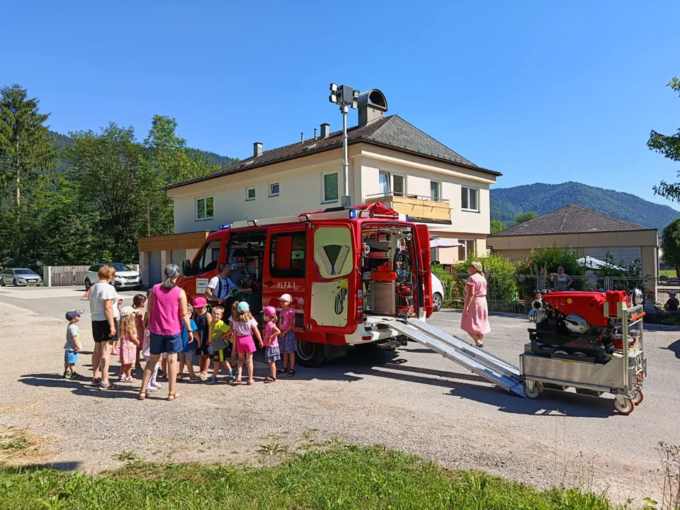 eine Gruppe von Menschen, die neben einem roten Feuerwehrauto stehen