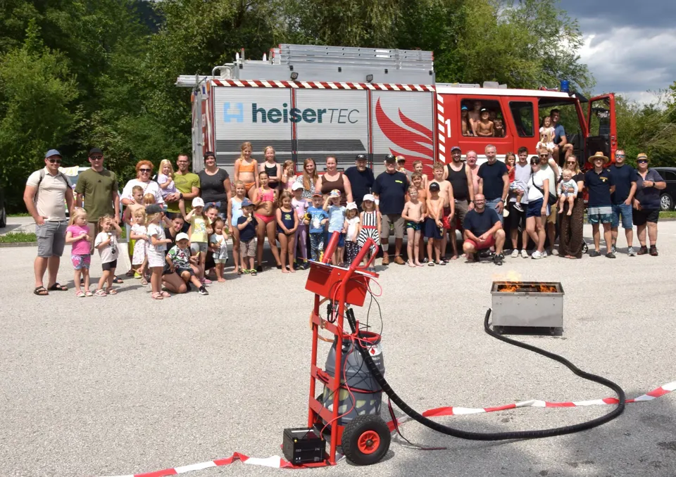 Eine Gruppe von Menschen steht vor einem Feuerwehrauto.