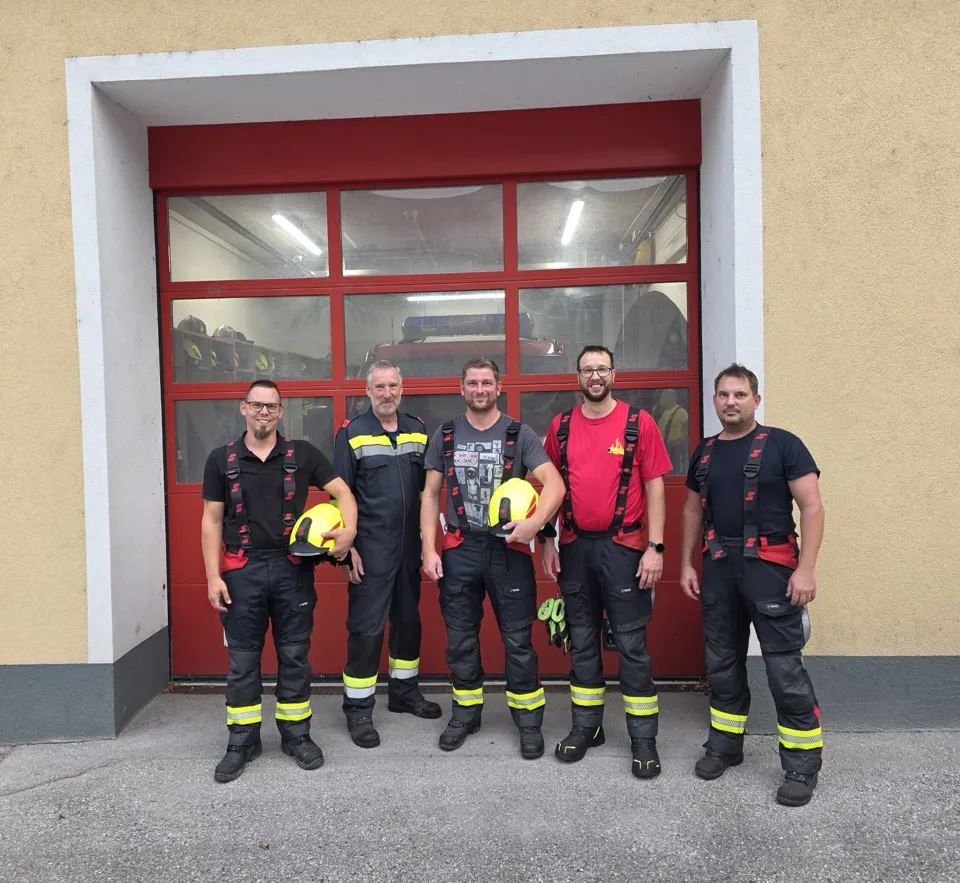Eine Gruppe von Männern in Feuerwehruniformen steht vor einer Feuerwache.