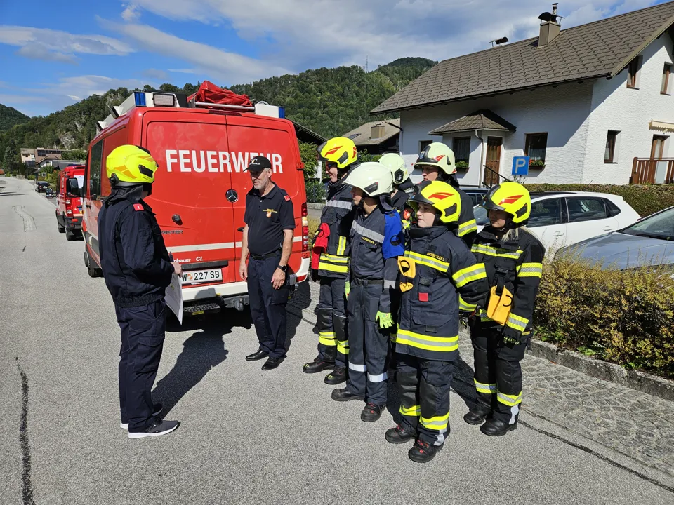 Eine Gruppe von Menschen in Feuerwehruniformen steht vor einem roten Feuerwehrwagen.