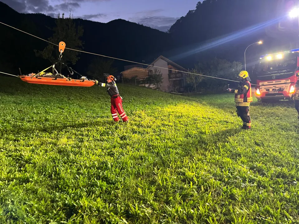 eine Gruppe von Feuerwehrleuten, die eine Schlinge tragen, die an einem Seil befestigt ist