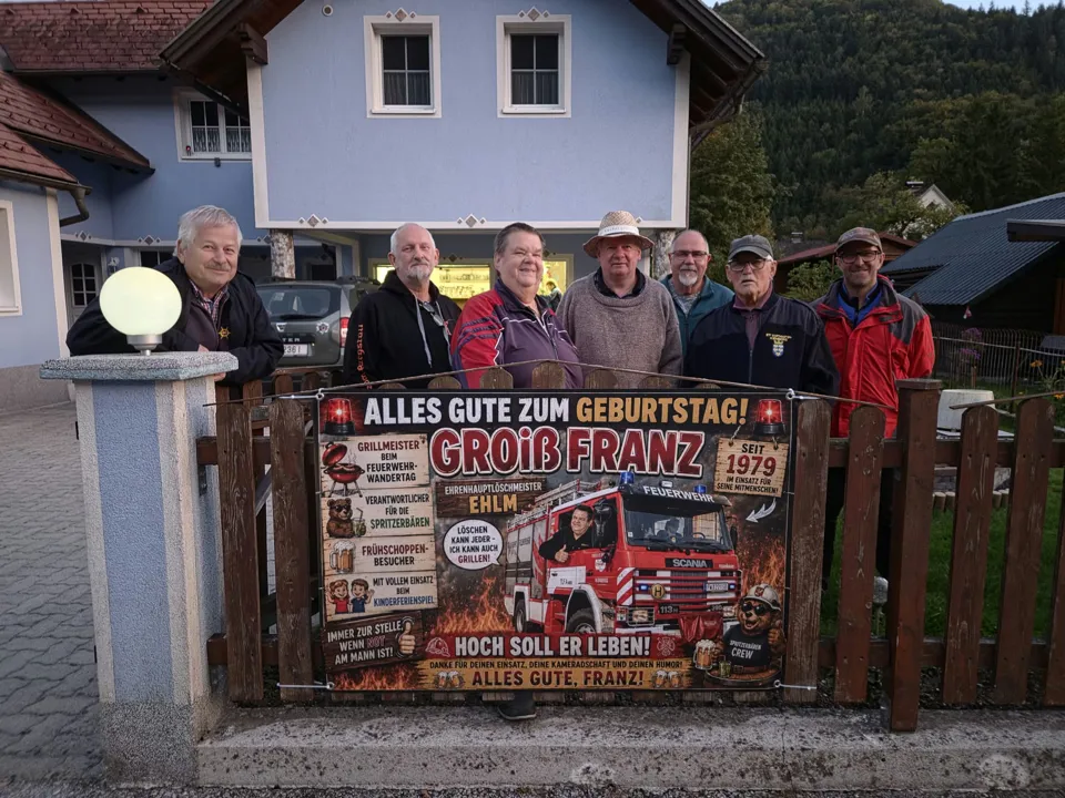 Eine Gruppe von Menschen steht vor einem Zaun.