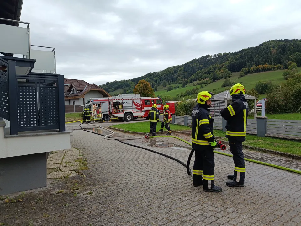 Eine Gruppe von Feuerwehrleuten steht vor einem Gebäude.
