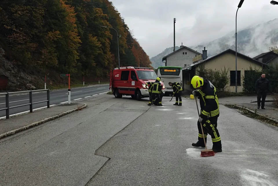 Eine Gruppe von Feuerwehrleuten fegt die Straße.