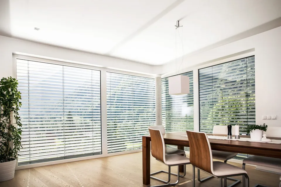 Ein Esstisch und Stühle in einem Raum mit Jalousien.
