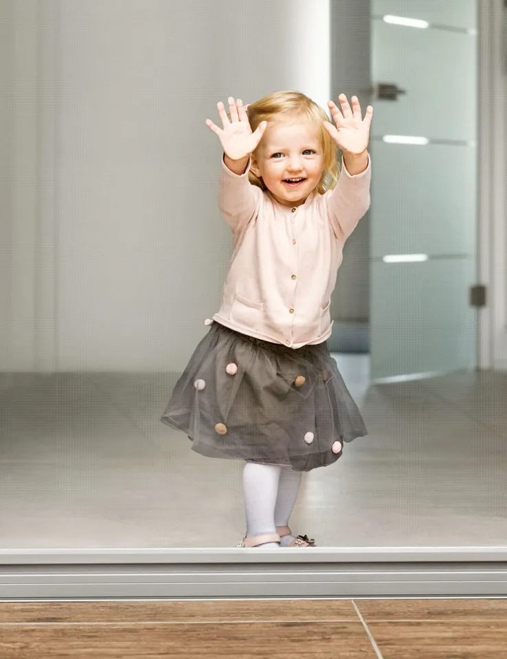 Ein Kind steht auf einer Kante mit erhobenen Händen.