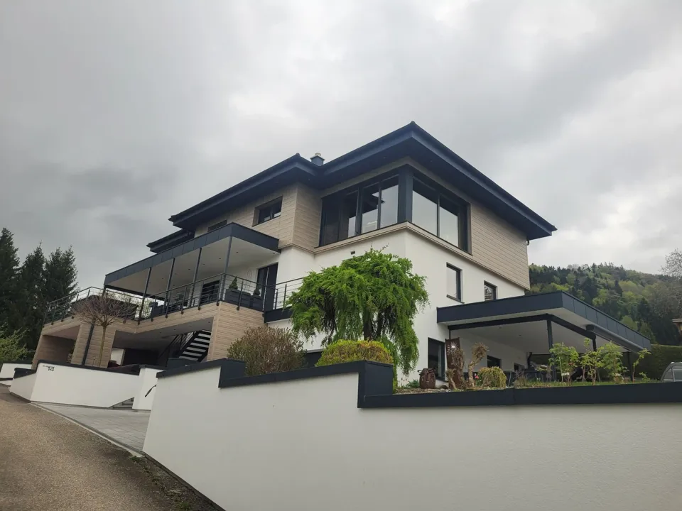 ein Haus mit einer weißen Wand und einem schwarzen Dach