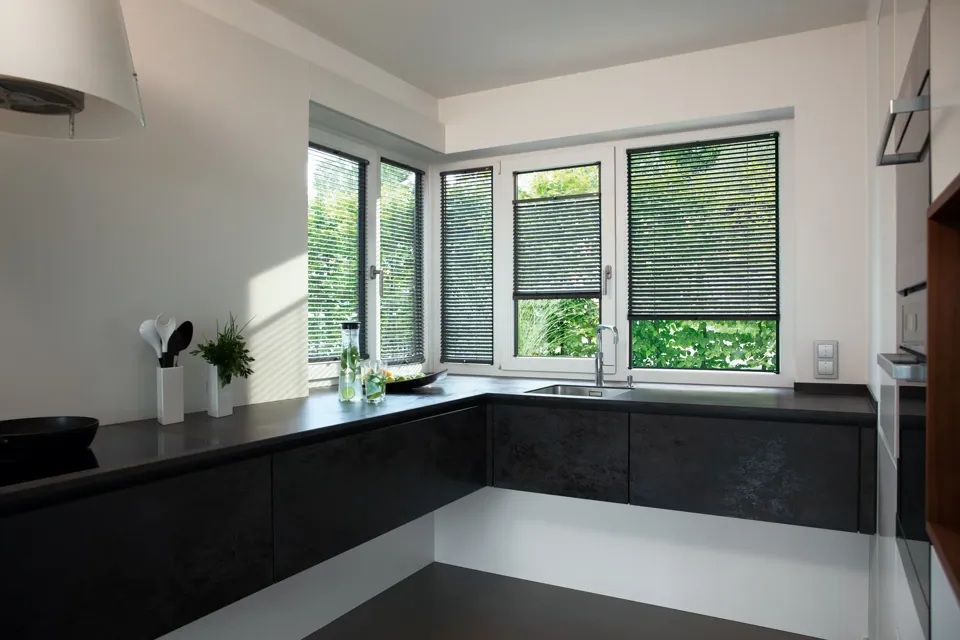 Eine Küche mit schwarzen Arbeitsplatten und Fenstern.