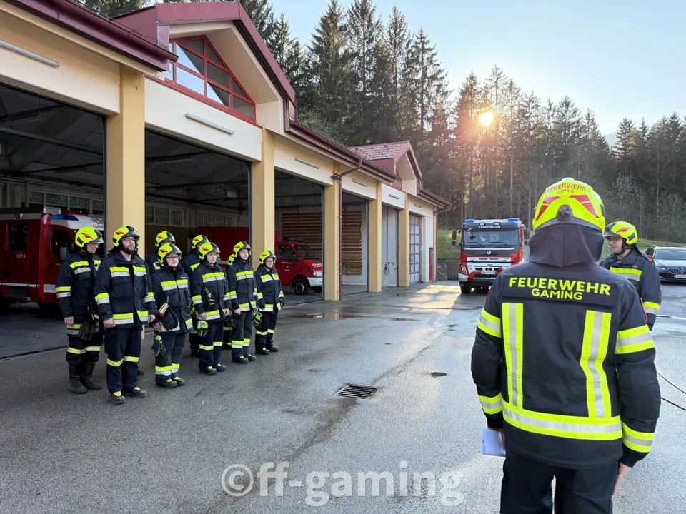 Eine Gruppe von Feuerwehrmännern steht vor einer Feuerwache.