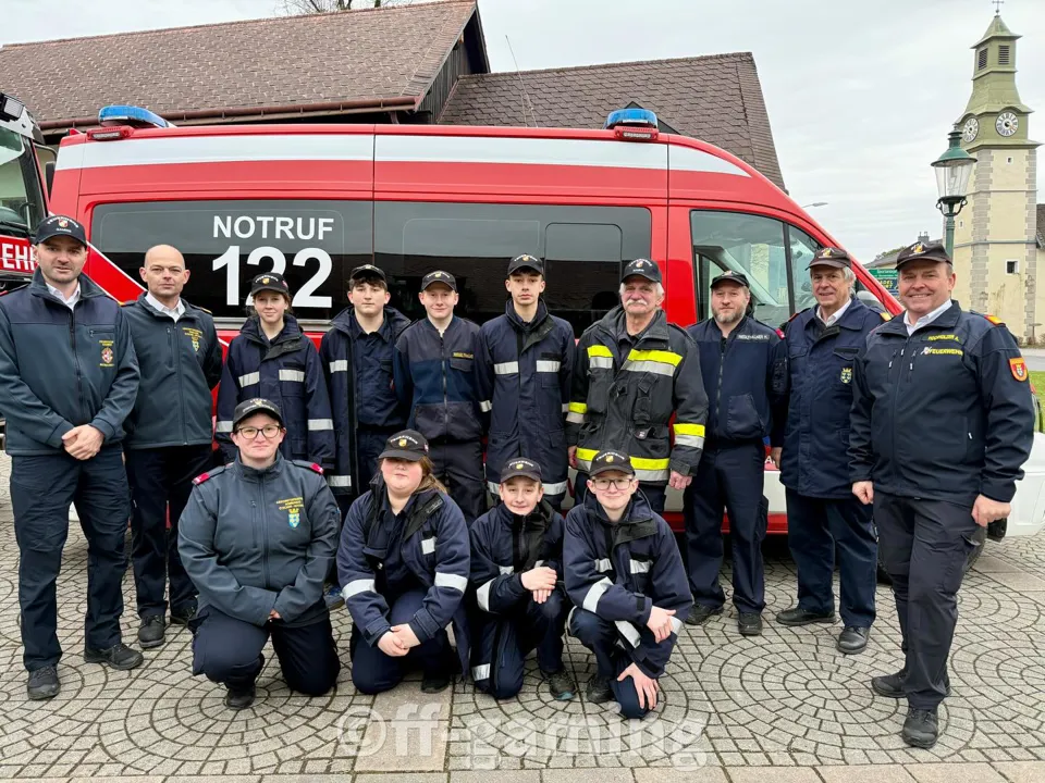 Eine Gruppe von Menschen posiert für ein Foto vor einem roten Fahrzeug.