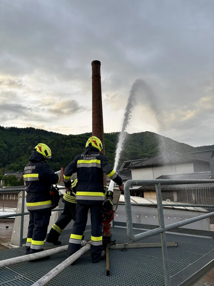 Eine Gruppe von Feuerwehrleuten, die Wasser aus einem Schlauch spritzen.