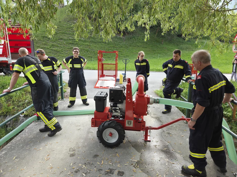 Eine Gruppe von Feuerwehrleuten steht um eine Maschine herum.
