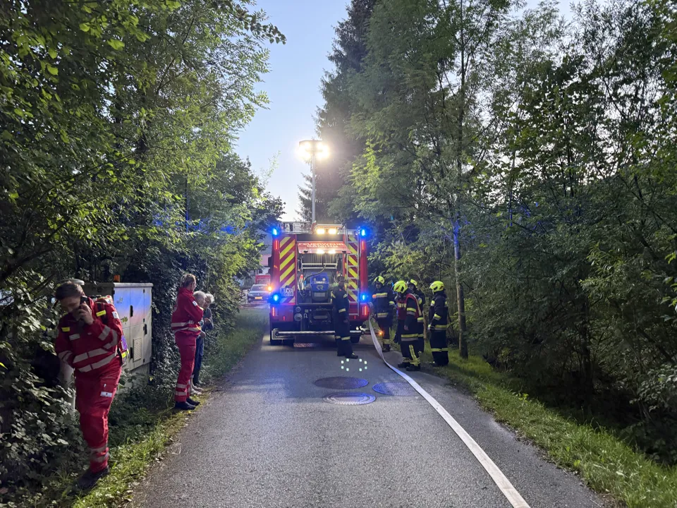 eine Gruppe von Feuerwehrleuten, die neben einem Feuerwehrauto stehen