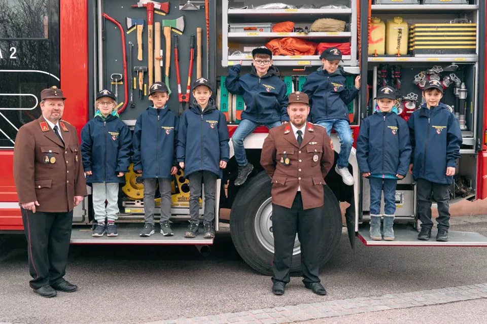 eine Gruppe von Kindern steht auf der Rückseite eines Feuerwehrautos