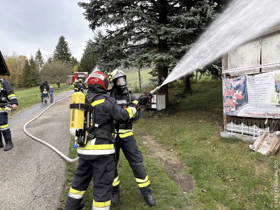 Ein Feuerwehrmann spritzt Wasser auf ein Gebäude.