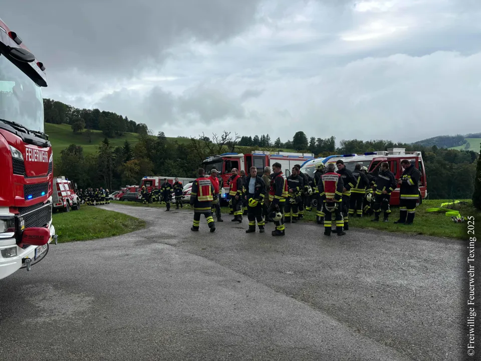 Eine Gruppe von Feuerwehrleuten steht vor einer Straße.