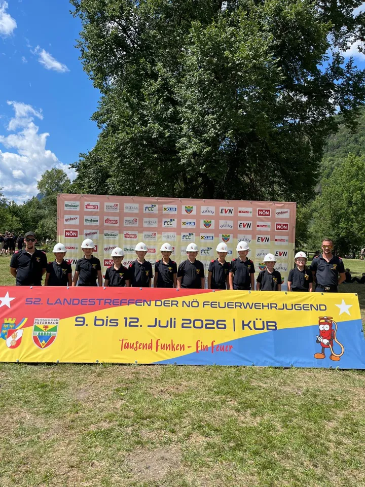 Eine Gruppe von Menschen in Uniform steht vor einem Banner.