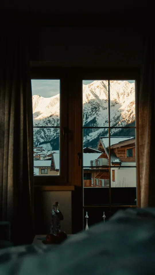 Ein Fenster mit einer verschneiten Bergkette im Hintergrund.