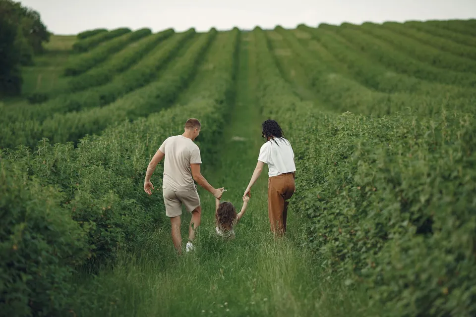 Eine Gruppe von Menschen hält sich an den Händen auf einem Feld voller Pflanzen.