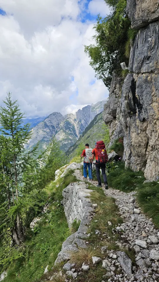 Zwei Personen wandern auf einem felsigen Pfad.
