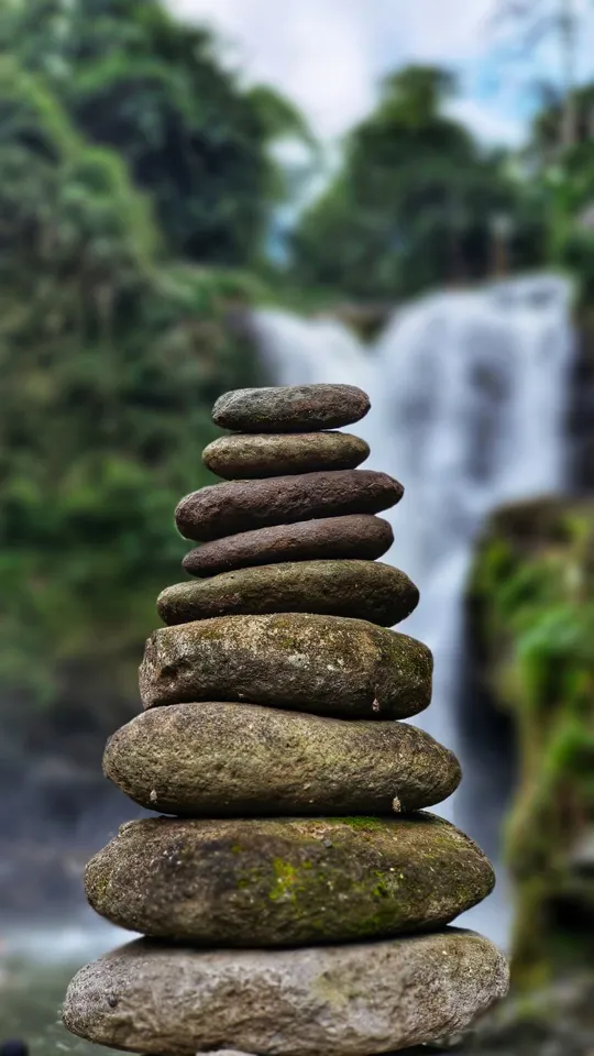 ein Stapel Steine vor einem Wasserfall