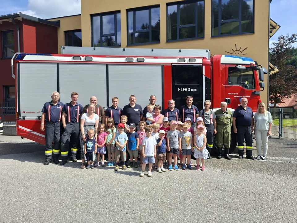 Eine Gruppe von Menschen posiert für ein Foto vor einem Feuerwehrauto.