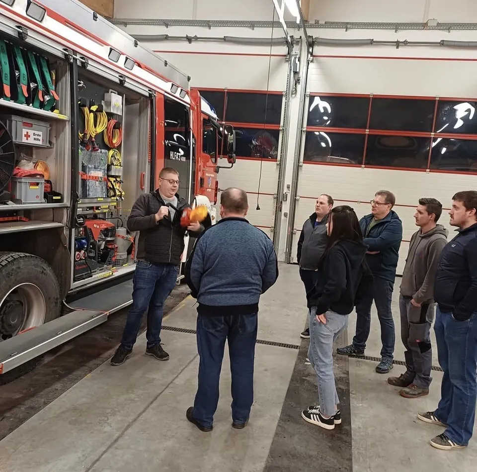 eine Gruppe von Menschen, die um ein Feuerwehrauto stehen