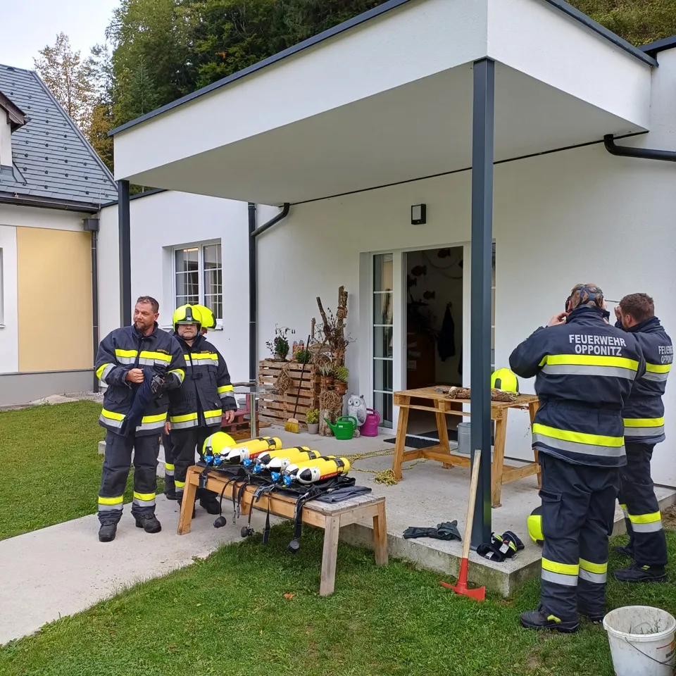 eine Gruppe von Feuerwehrleuten, die vor einem Haus stehen