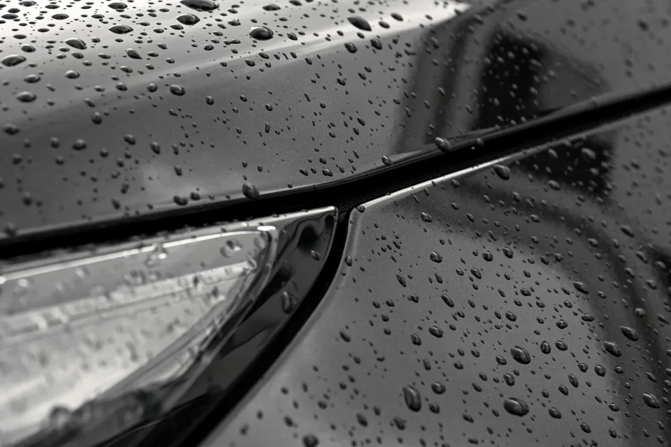 Nahaufnahme eines schwarzen Autos mit Wassertropfen darauf.
