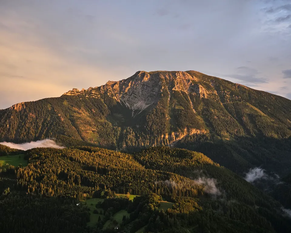 ein Berg mit Bäumen und Wolken