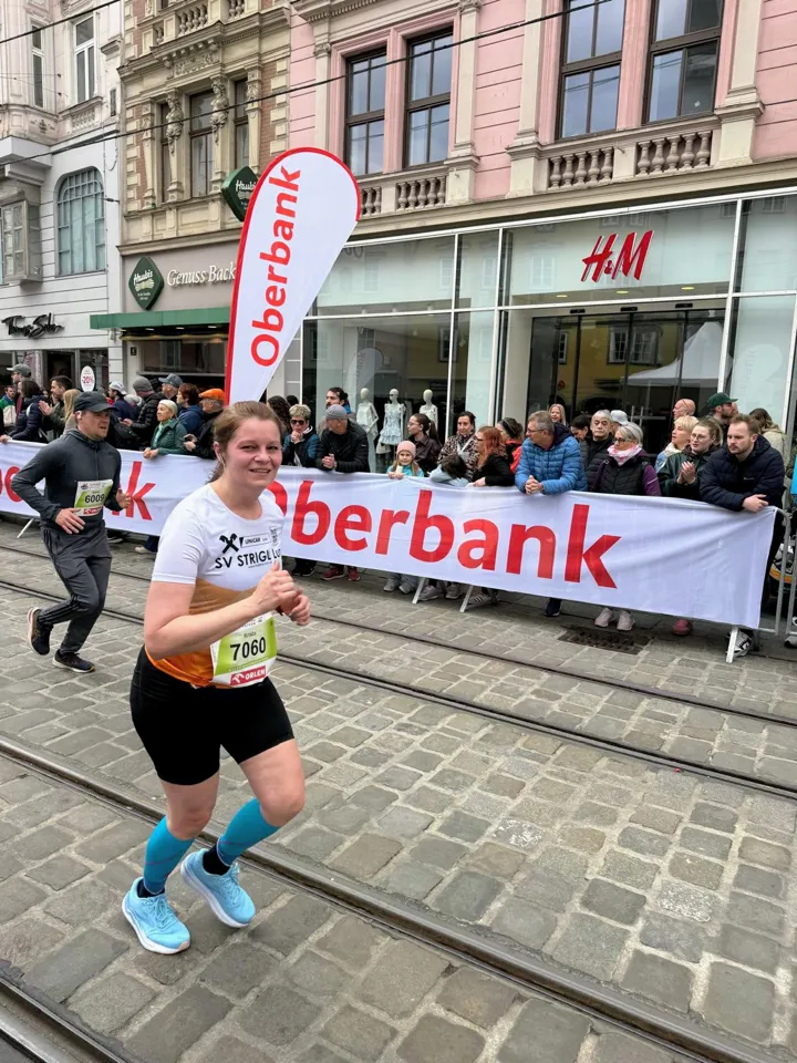 Eine Person läuft auf einer Straße, hinter ihr eine Menschenmenge.