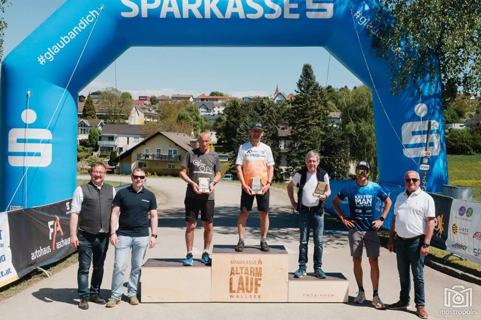eine Gruppe von Männern, die auf einem Podium mit Trophäen stehen