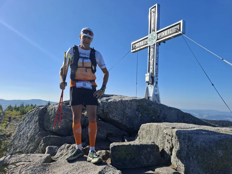 eine Person, die auf einem Felsen steht, auf dem ein Kreuz steht