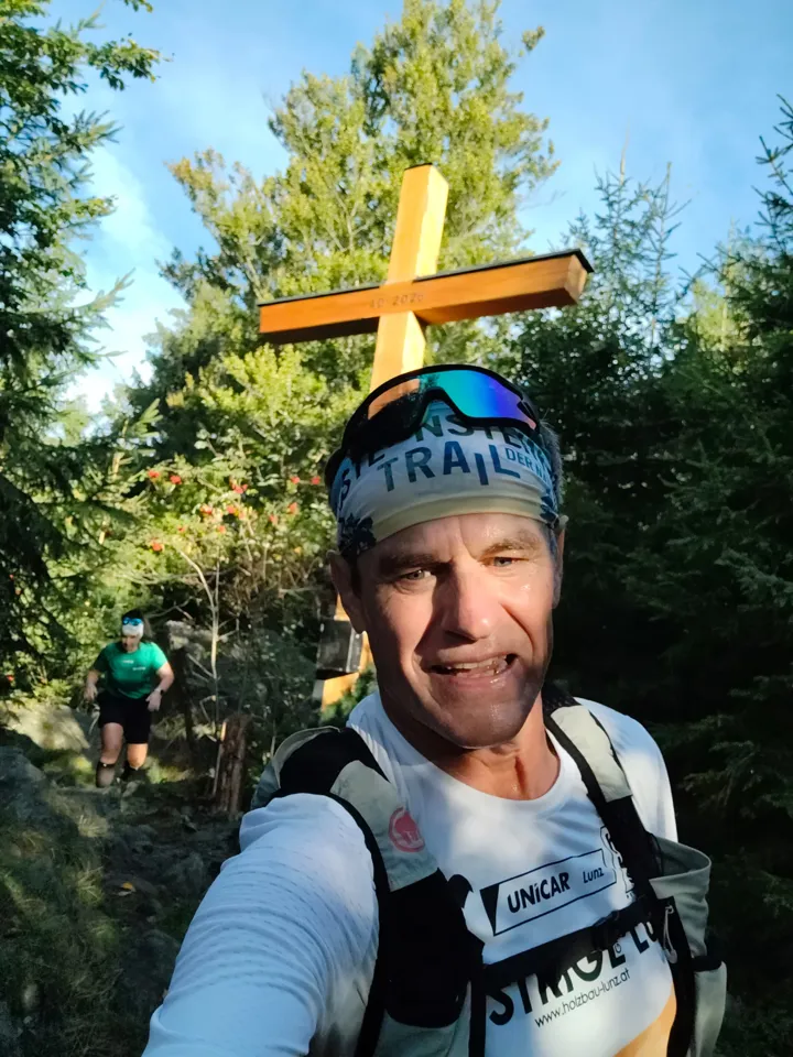 Eine Person macht ein Selfie vor einem Kreuz.